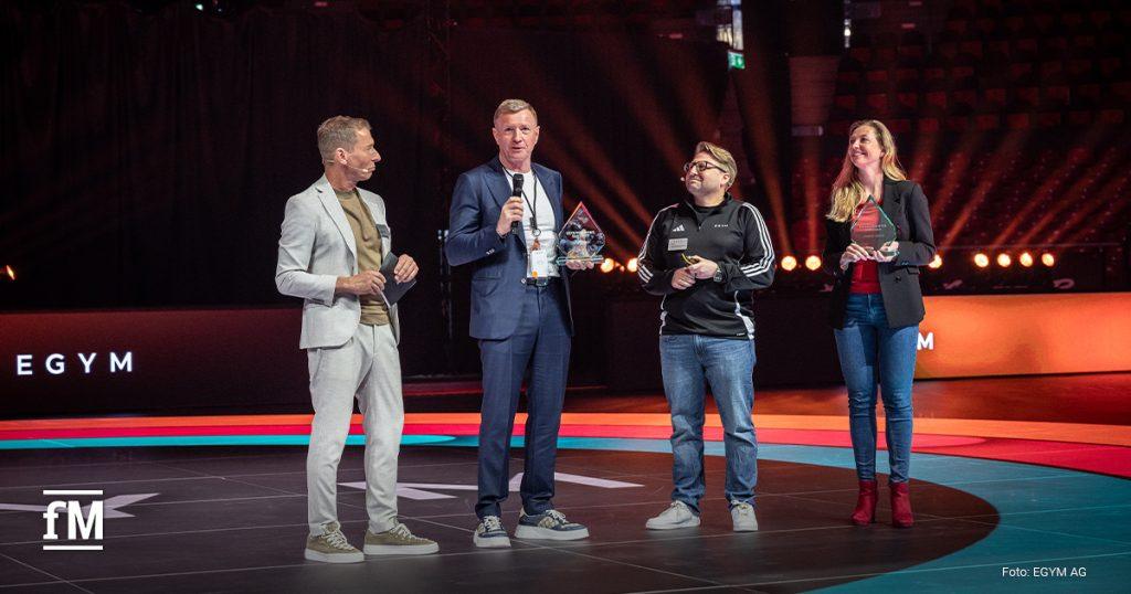 Ehre für besondere Verdienste: Christin und Mario Görlach (Zweiter von links) erhalten den ersten EGYM Achievement Award für ihren Beitrag zum Unternehmenserfolg, hier mit Moderator Markus Othmer (links) und EGYM CEO Philipp Roesch-Schlanderer