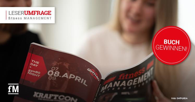 Zwei Personen blättern in einer Ausgabe des Magazins fitness MANAGEMENT international. Ein roter Kreis mit der Aufschrift 'Buch gewinnen!' hebt eine Gewinnaktion zur Leserumfrage hervor.