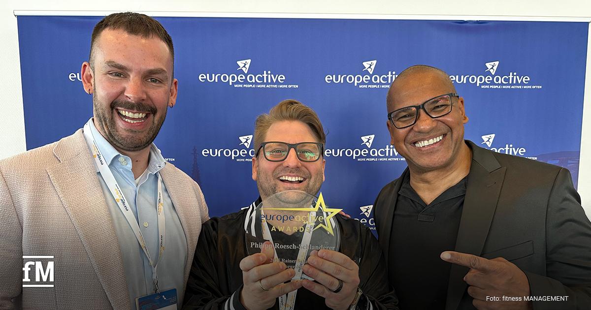 Drei lächelnde Männer stehen vor einer blauen 'EuropeActive'-Fotowand. Der Mann in der Mitte hält stolz einen 'Rainer Schaller Entrepreneurship Award' in den Händen, auf dem der Name Philipp Roesch-Schlanderer zu lesen ist. Alle drei tragen Namensschilder und wirken gut gelaunt. Der rechte Mann zeigt mit dem Finger auf den Award-Gewinner.