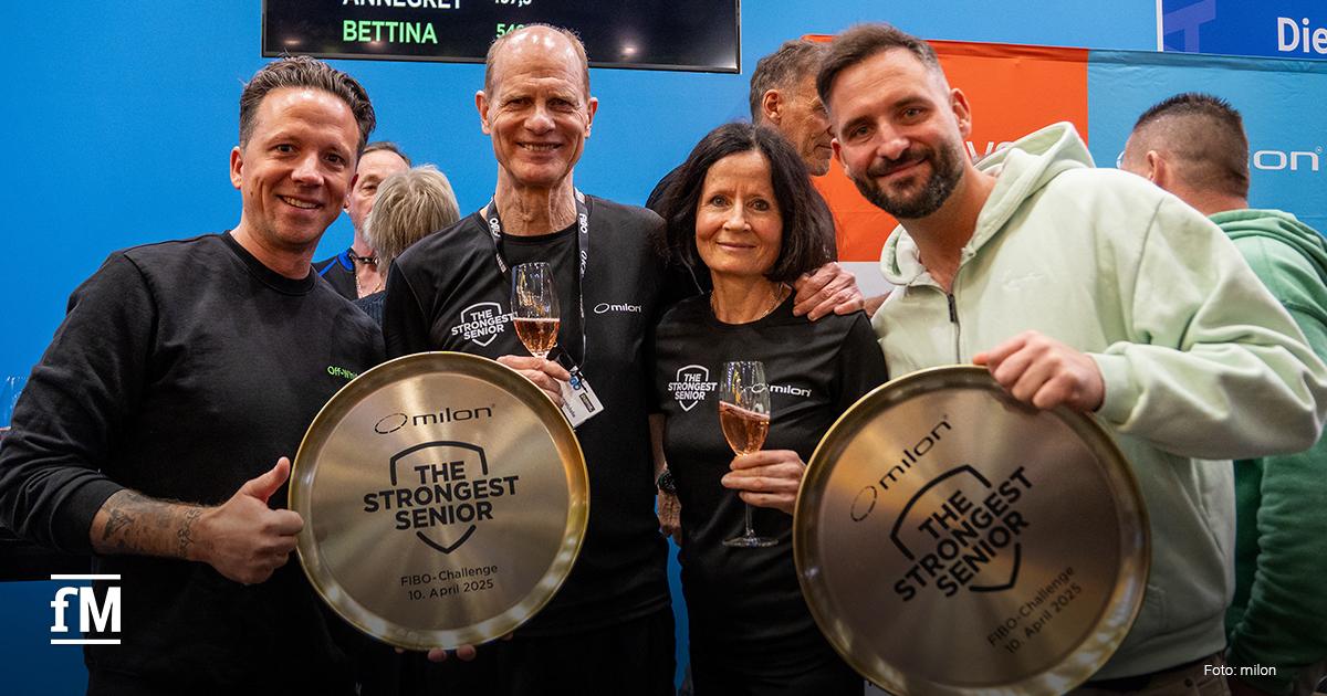 Gruppenfoto bei der FIBO-Challenge 'The Strongest Senior' am 10. April 2025: Zwei Seniorensieger halten ihre milon-Auszeichnungstabletts in der Hand, begleitet von den stolzen Studiobetreibern Timo Stickeln und Bartosch Mlynarczyk. Alle tragen schwarze bzw. sportliche Kleidung, halten Sektgläser und lächeln in die Kamera.