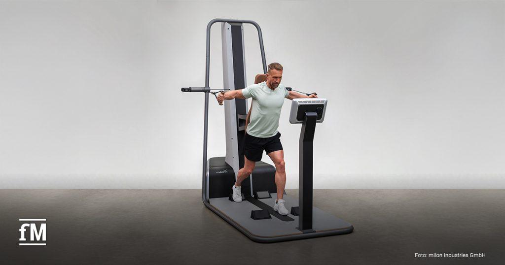 Im Bild trainiert ein Mann im Stehen an der neuen milon X Trainingsstation