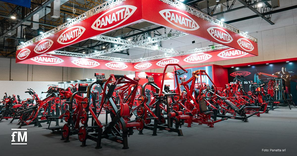 Auf dem Bild ist ein FIBO-Messestand mit zahlreichen roten Panatta-Fitnessgeräten zu sehen. Über den Geräten schwebt ein großes, rotes Schild mit dem weißen Logo „PANATTA“ auf rotem Grund.