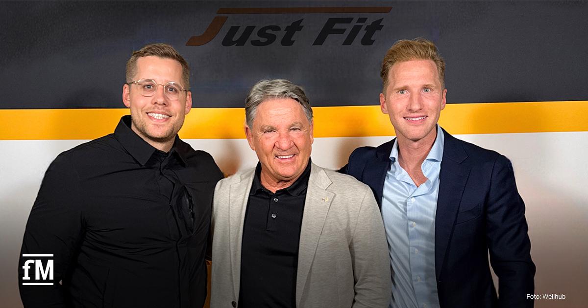 Drei Männer (v.l. Eric Krahnert (Wellhub), Frank Böhme (Just Fit) und Samuel Turnwald (Wellhub)) stehen nebeneinander vor einer Wand mit dem Just Fit-Logo.