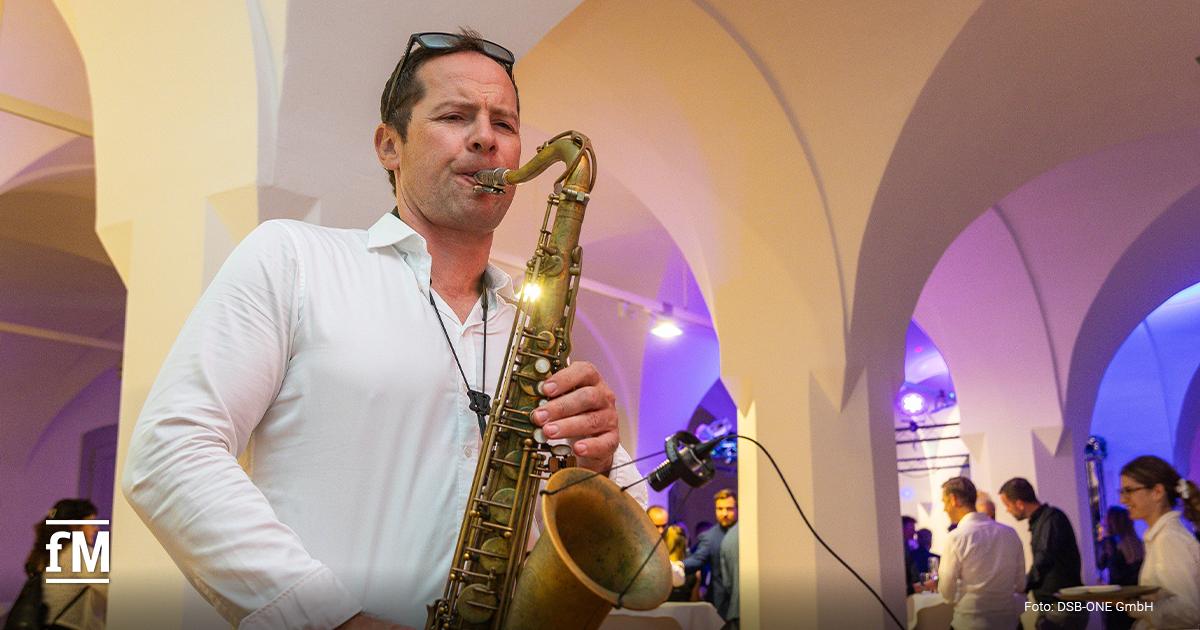 Ein Musiker spielt Saxofon bei einem Netzwerkabend in stilvoller Event-Atmosphäre mit beleuchteten Gewölben.