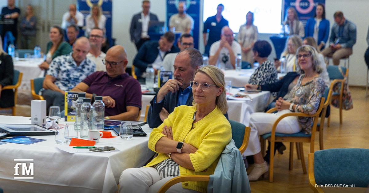 Zahlreiche Teilnehmerinnen und Teilnehmer sitzen an runden Tischen und hören konzentriert einem Vortrag beim ONE.FUTURE Netzwerktreffen zu.