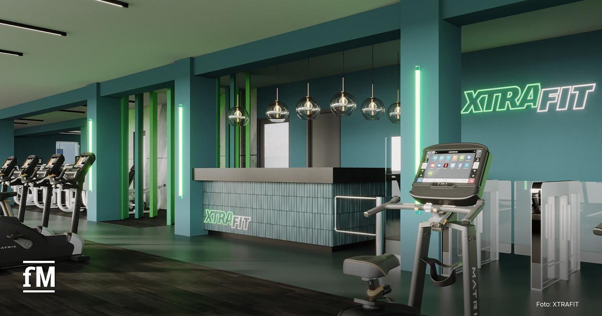 Modernes Fitnessstudio mit türkisfarbenem Design und stilvoller Beleuchtung. Im Vordergrund stehen Cardiogeräte, rechts eine Rezeption mit dem Logo 'XTRAFIT'. Helle Atmosphäre mit klaren Linien und Glasdetails.