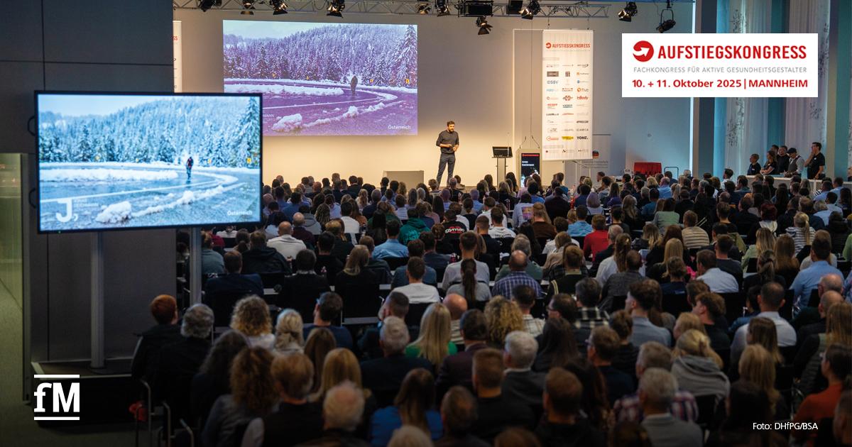 Der Extrem-Sportler Jonas Deichmann steht auf der Bühne in einem vollbesetzten Saal beim Aufstiegskongress 2024 und berichtet von seinem Triathlon um die Welt. Auf Bildschirmen sind Impressionen vom Triathlon zu sehen. Oben rechts ist das Logo des Aufstiegskongress mit dem Datum für 2025: 10. und 11. Oktober.
