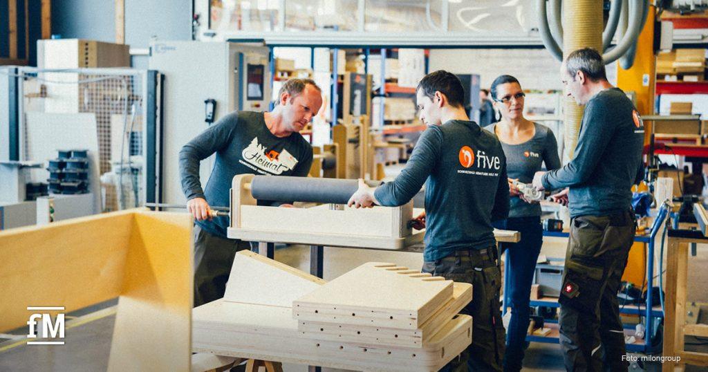 Vier five-Mitarbeitende in dunklem Shirt arbeiten gemeinsam an einem five Gerät in der Werkstatt.