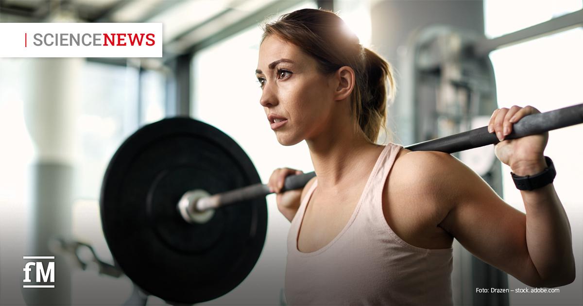 Junge Frau trainiert im Fitnessstudio mit einer Langhantel auf den Schultern, Fokus auf Konzentration und Anstrengung beim Krafttraining