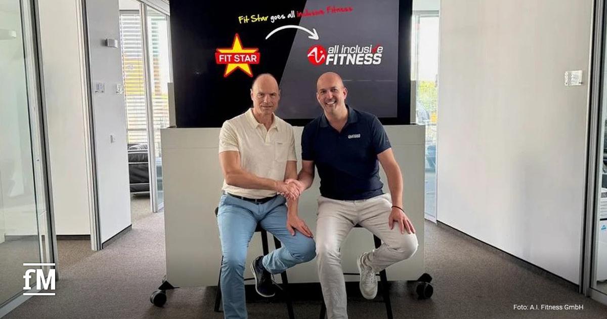 Zwei Männer sitzen nebeneinander und schütteln sich die Hand. Hinter ihnen zeigt ein Bildschirm die Logos von 'Fit Star' und 'all inclusive FITNESS' mit dem Text 'Fit Star goes all inclusive Fitness'.