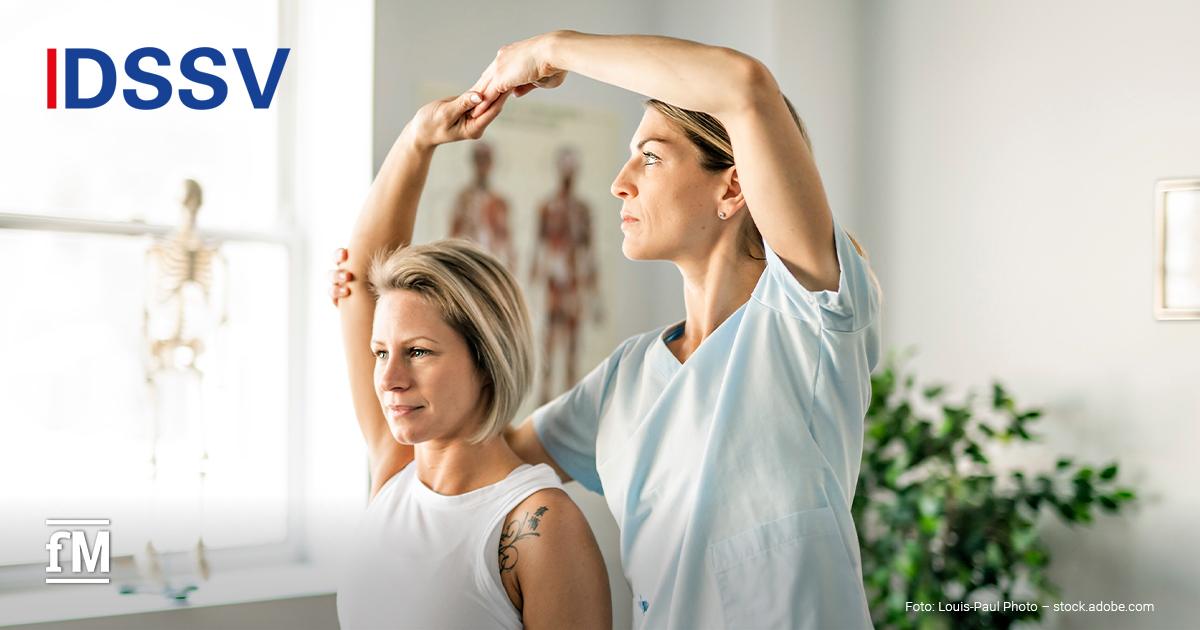 Eine Physiotherapeutin in weißer Kleidung führt mit einer Patientin eine Schulter- und Armbewegungsübung durch. Im Hintergrund sind ein Skelettmodell, anatomische Poster und eine Pflanze zu sehen.