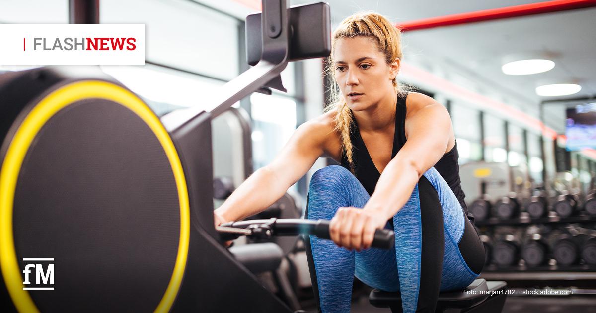 Eine sportliche Frau trainiert konzentriert auf einem Technogym Rudergerät in einem modernen Fitnessstudio. Sie trägt blaue Leggings und ein schwarzes Top. Links oben die Rubrik 'Flashnews' in Großbuchstaben, erstes Wort grau, zweites Wort rot.