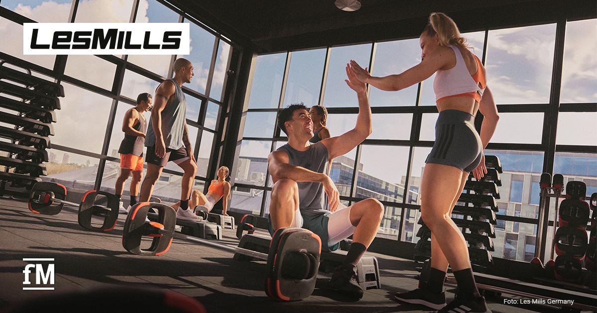Zwei Personen im Fitnessstudio geben sich ein High-Five, umgeben von Hanteln und Steppern.