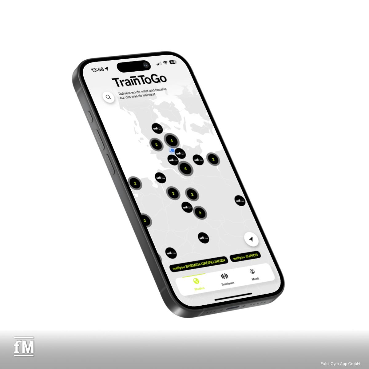 Ein leicht schräg fotografiertes Smartphone mit geöffneter TrainToGo-App. Auf dem Bildschirm ist eine Landkarte mit mehreren schwarzen Kreisen und grünen Zahlen zu sehen.