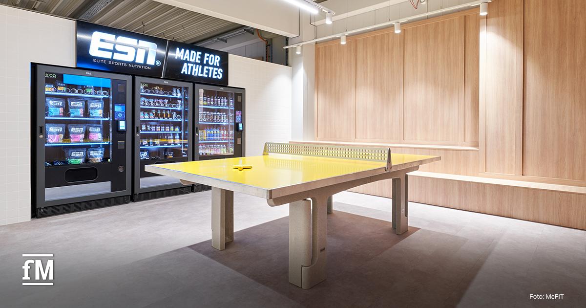 Gelbe Tischtennisplatte vor einem ESN-Snackautomaten im neuen McFIT-Fitnessstudio Hamburg-Stellingen
