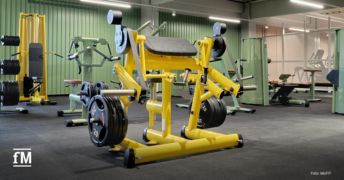 Gelbes gym80 Trainingsgerät mit Gewichtsscheiben in einem modernisierten McFIT-Fitnessstudio.