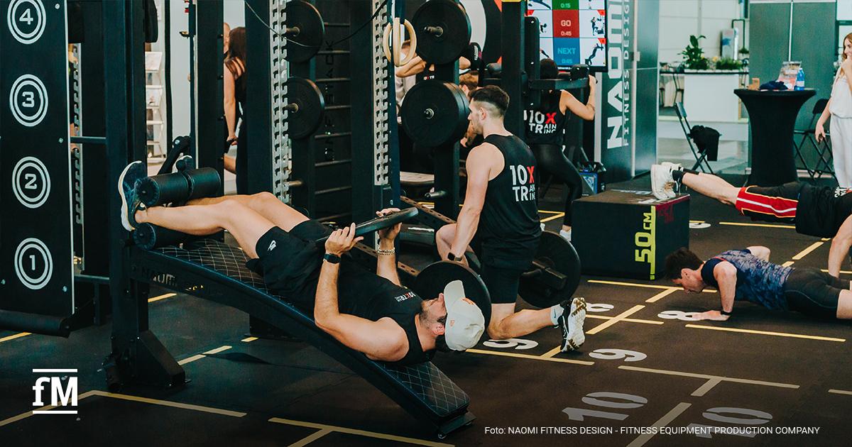 Mehrere Personen trainieren gleichzeitig an Geräten und auf Matten im Fitnessstudio.