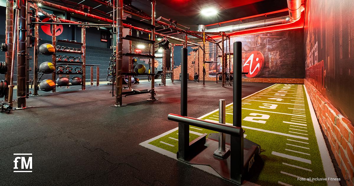 Functional-Bereich mit Trainingsgeräten, Kettlebells und einer Kunstrasenbahn mit Markierungen.
