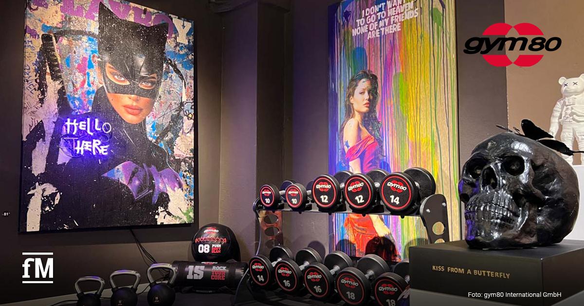 Hanteln, Kettlebells und Pop-Art-Bilder in einer Ausstellung mit Skulptur.
