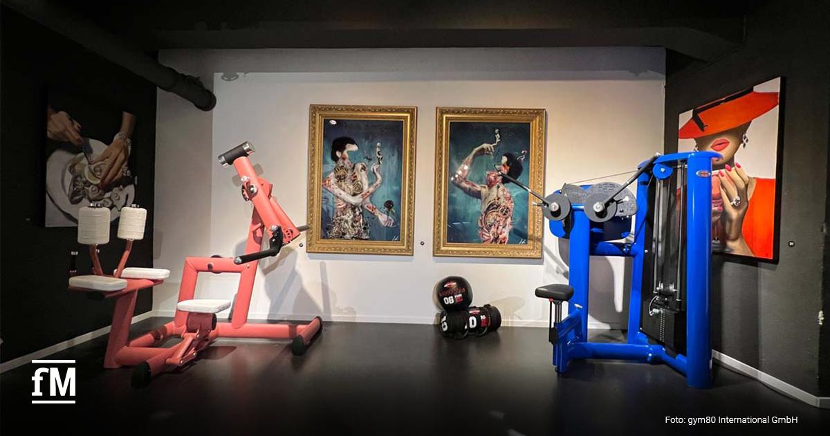 Zwei Fitnessgeräte vor bunten Pop-Art-Gemälden in einer Ausstellung.
