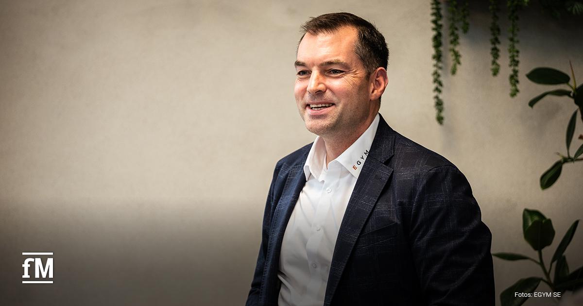 in Mann im Anzug spricht vor Publikum, EGYM-Logo am Hemdkragen sichtbar