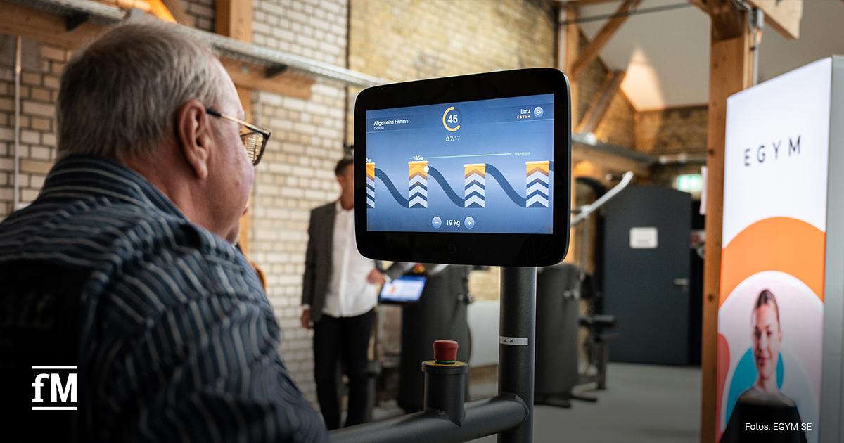 Ein älterer Mann blickt auf einen Bildschirm mit Fitnessdaten in einer Trainingsumgebung