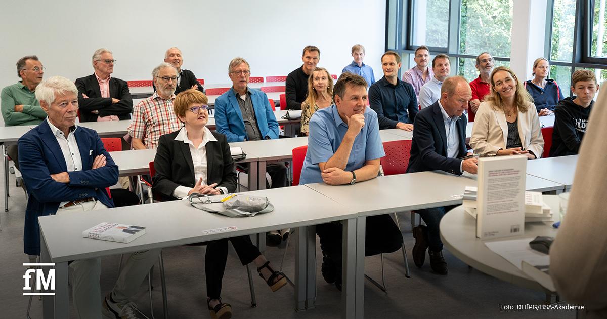 Eine Gruppe von Männern und Frauen sitzt in einem Seminarraum und hört aufmerksam der Buchvorstellung zu. Prof. Dr. Thomas Wessinghage sitzt vorne links in der ersten Reihe.