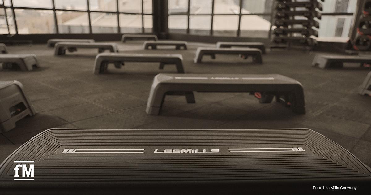 Mehrere schwarze LES MILLS SMARTSTEPs in einem leeren Kursraum aufgestellt.