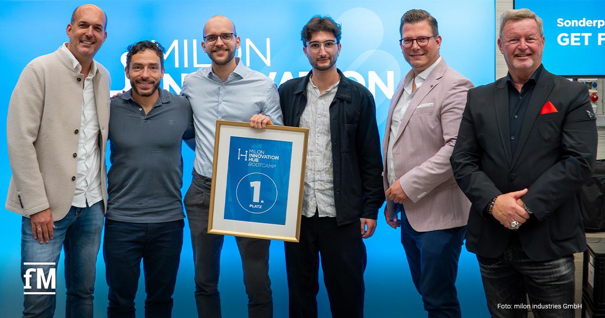 Gruppenfoto von sechs Personen beim milon Innovation Hub Bootcamp. Zwei Männer in der Mitte halten eine Urkunde mit der Aufschrift '1. Platz EXERSIGHT'. Alle stehen vor blauem Hintergrund und lächeln.