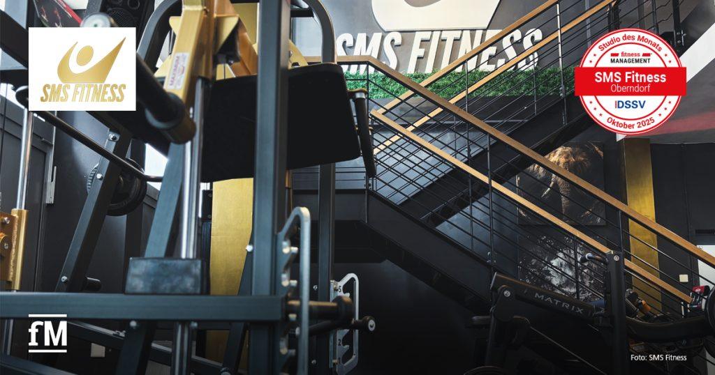 Blick auf Fitnessgeräte im Vordergrund und eine schwarze Treppe mit grünem Deko-Element im Hintergrund, an der Wand das Logo SMS Fitness.