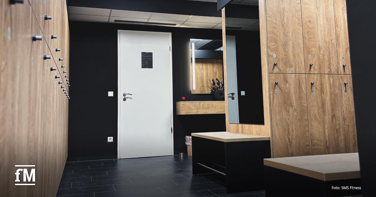 Umkleide mit Garderobenschränken, großem Spiegel und Sitzbank, in modernem Design in schwarz und Holz.