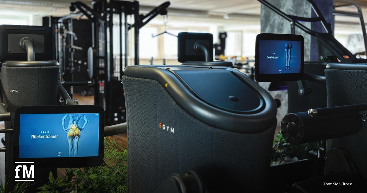 Nahaufnahme von modernen EGYM-Geräten mit Displays, die Rücken- und Beinübungen anzeigen.