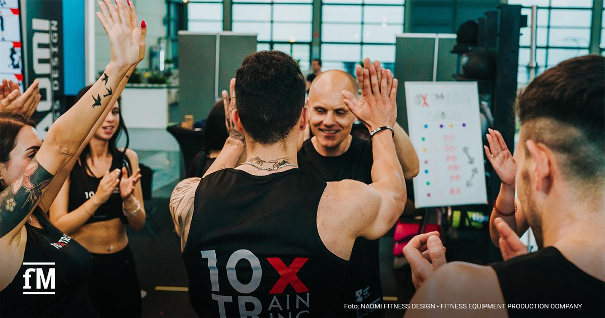 Im Fitnessstudio klatschen sich Menschen in Sportkleidung gegenseitig ab.