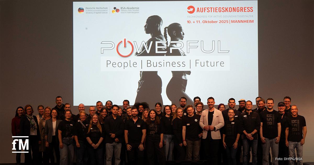 Eine große Gruppe von Menschen steht lächelnd vor dem Logo des Aufstiegskongress 2025. Es zeigt zwei Menschen, die Rücken an Rücken stehen, mit dem Motto 'Powerful. People | Business | Future'.