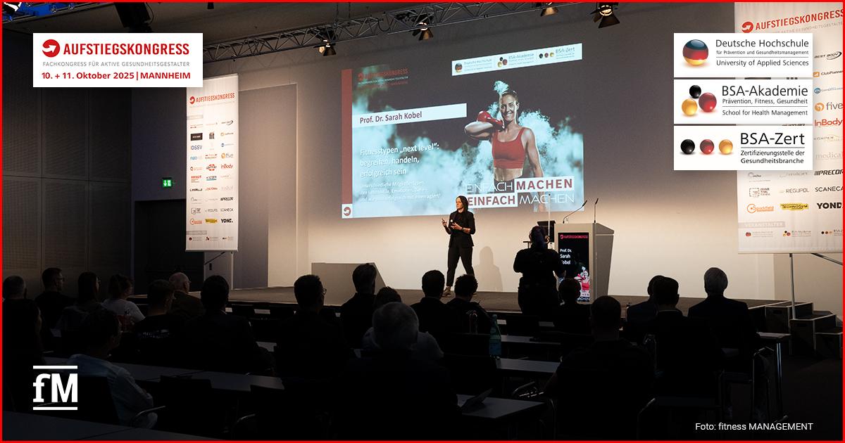 Auf der Bühne des Aufstiegskongresses 2025 steht eine Rednerin vor einer großen Leinwand und spricht zu einem Publikum. Auf der Leinwand ist die Präsentation von Prof. Dr. Sarah Kobel zum Thema 'Fitnesstypen next level' zu sehen.