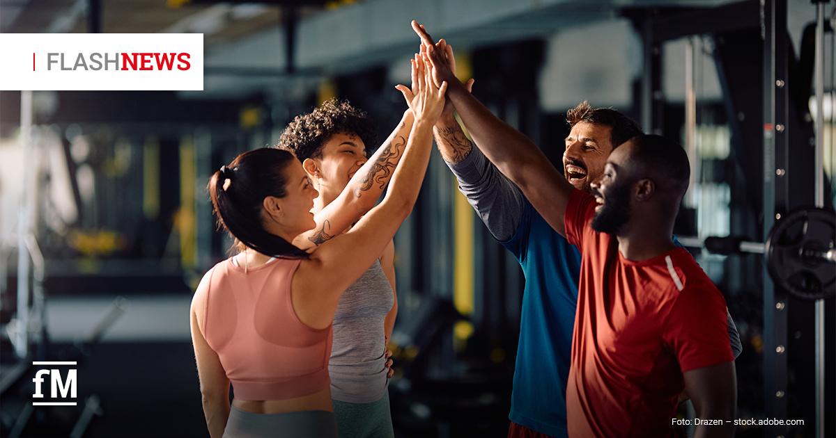 Vier Personen geben sich im Fitnessstudio freudig ein High-Five.
