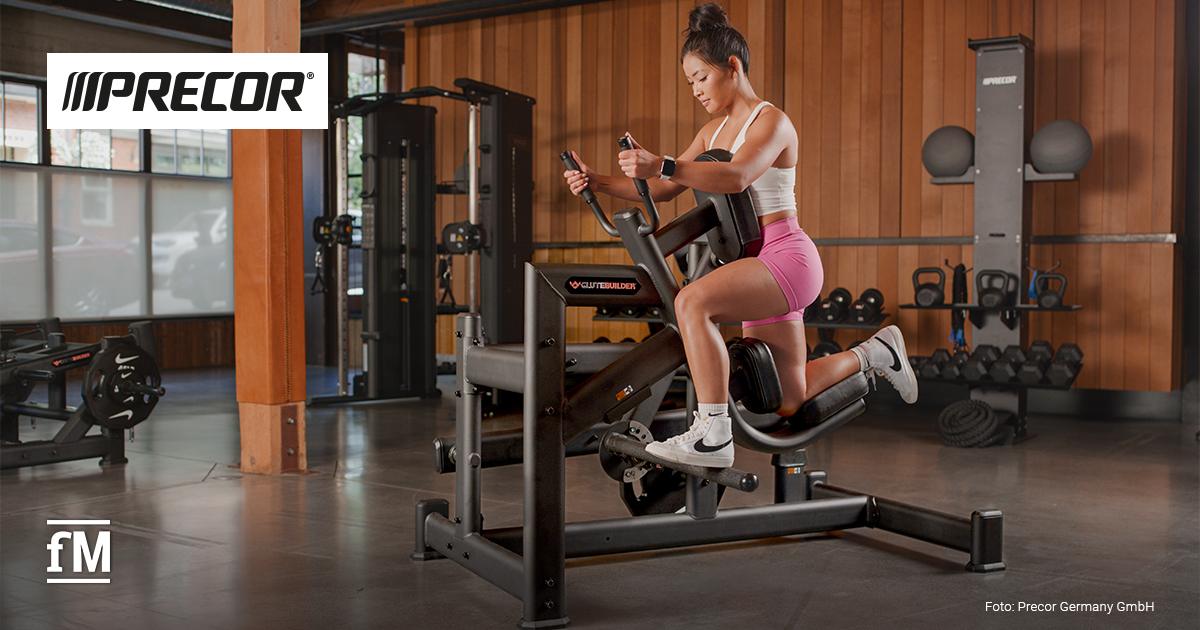 Person trainiert an einem Precor-Glutebuilder-Gerät in einem modernen Fitnessstudio. Links oben das Precor Logo, links unten das fM Signet.