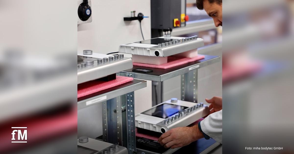 Person überprüft EMS-Steuergeräte von miha bodytec in einer Laborumgebung.