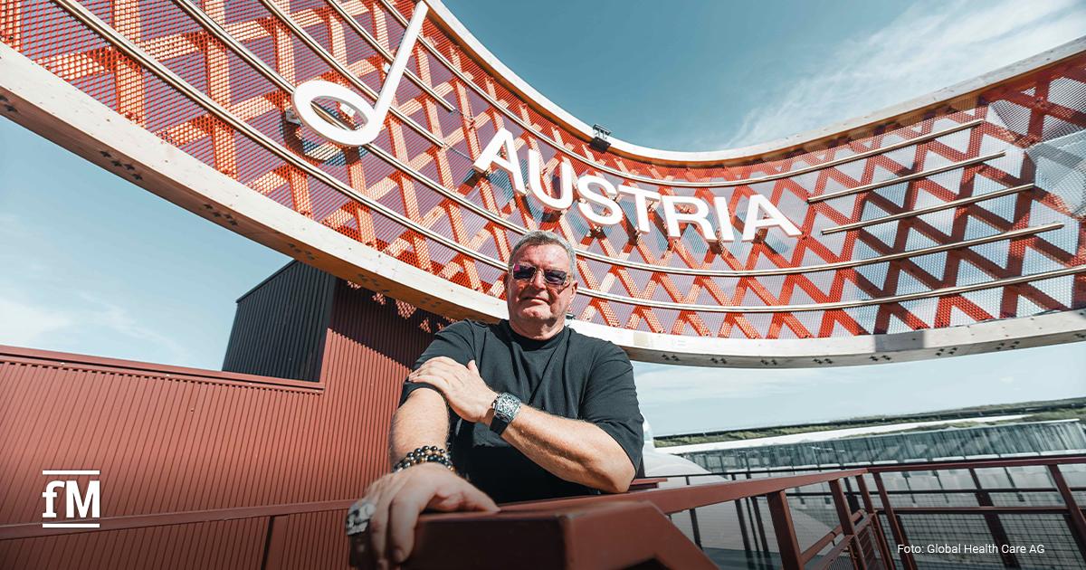 Mann steht vor dem Österreich-Pavillon mit großem Schriftzug „Austria“ und rotem Metallgitter.