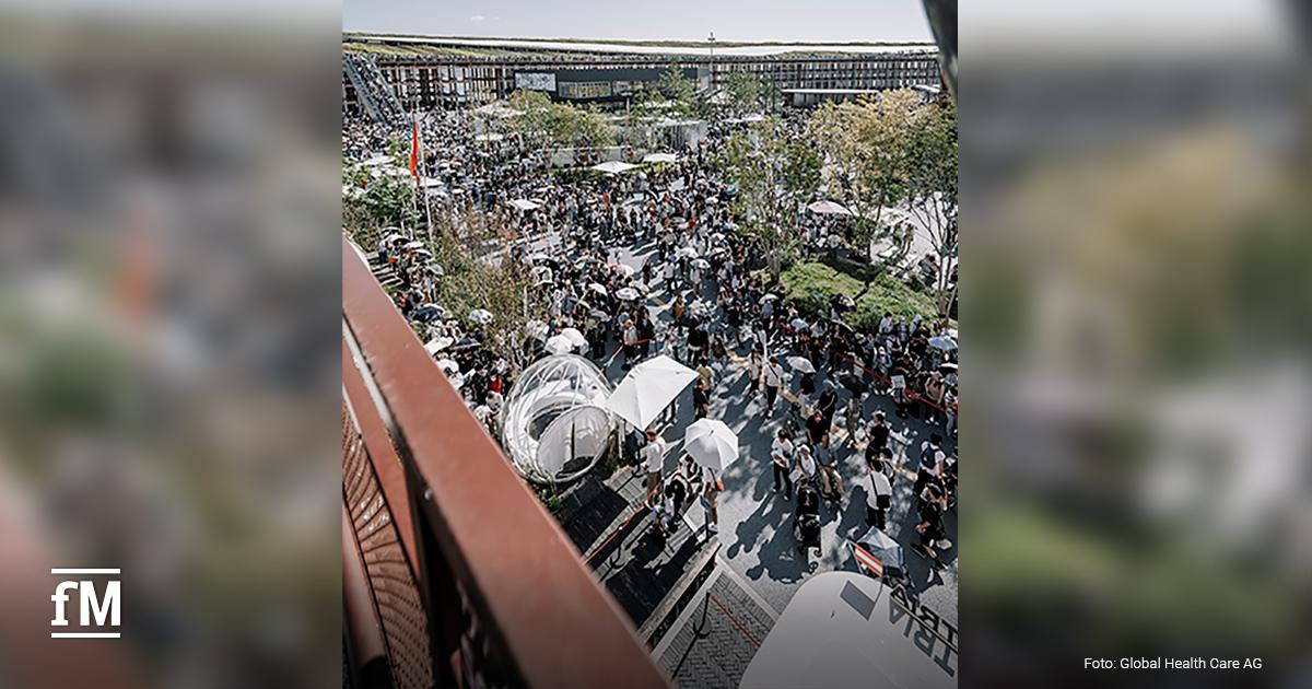 Große Menschenmenge unter Sonnenschirmen auf dem Außengelände der Expo 2025 in Osaka.