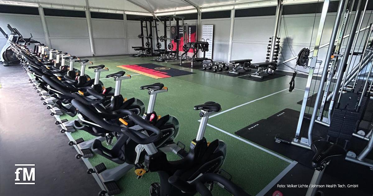 Zelt mit Indoorbikes, Hanteln und Kraftgeräten auf grünem Boden.