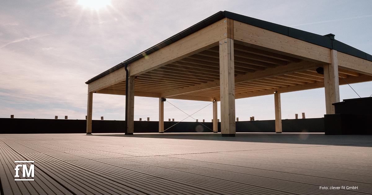 Holzüberdachte Dachterrasse mit moderner Konstruktion und weitem Blick in den Himmel bei Sonnenschein. Die Fläche wirkt gepflegt und bietet Platz für Outdoor-Aktivitäten.