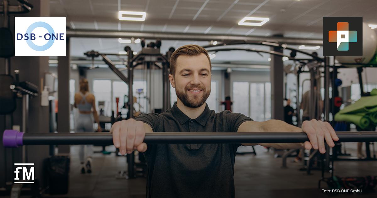 Ein Mann trainiert an einem Gerät in einem modernen Fitnessstudio und lächelt konzentriert. Im Hintergrund sind weitere Personen beim Training zu sehen. Links oben das Logo von DSB-ONE, rechts oben das Logo von Physio+.