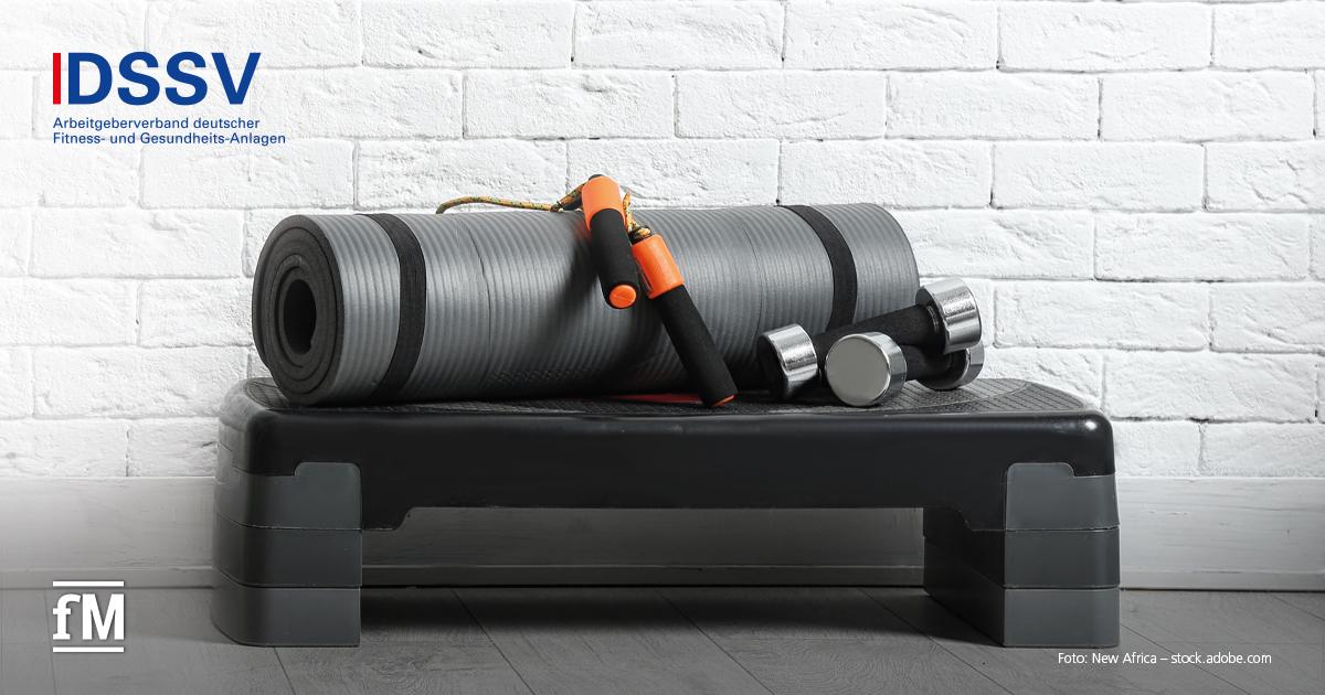 Graue Trainingsmatte, Kurzhanteln und Springseil auf einem Steppbrett, vor weißer Ziegelwand, links oben DSSV-Logo.