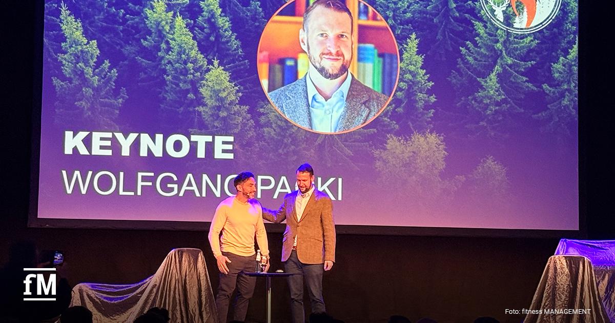 Keynote-Sprecher und Schmerztherapie-Experte Wolfgang Packi steht auf der Bühne vor einer großen Projektionswand