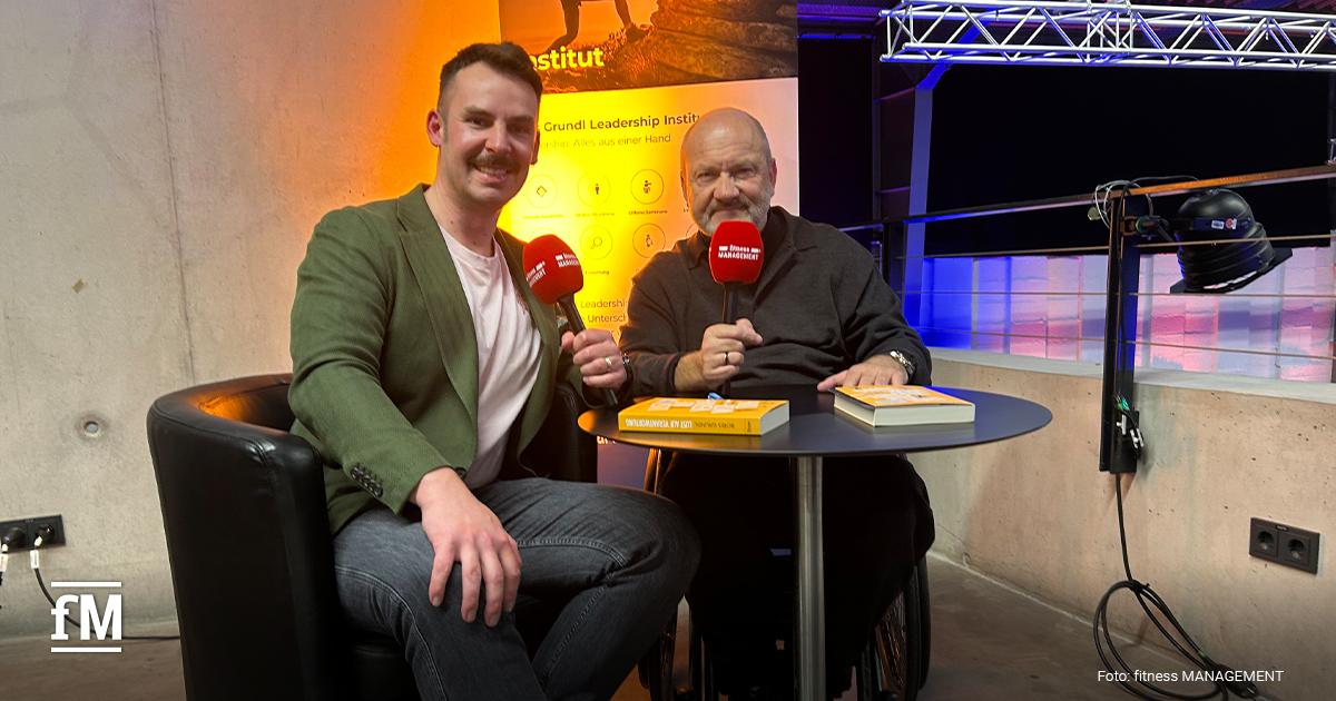 Zwei Personen sitzen vor einem Banner mit fm-Mikrofonen.