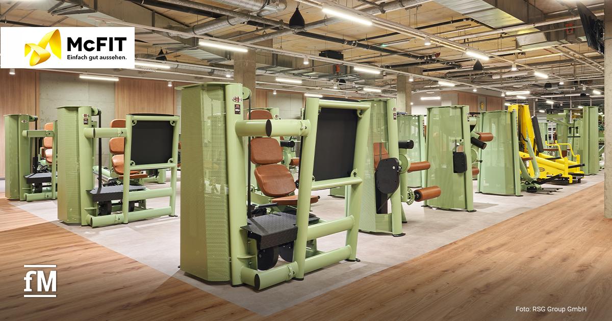Bereich mit mehreren grünen Kraftmaschinen und braunen Polstern auf hellem Boden im McFIT Berlin-Prenzlauer Berg.