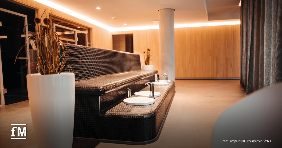 Großzügiger Fußbadbereich mit gefliester Sitzbank, modernen Waschschalen und warmem Lichtdesign im puls fit & wellnessclub Stuttgart-Vaihingen