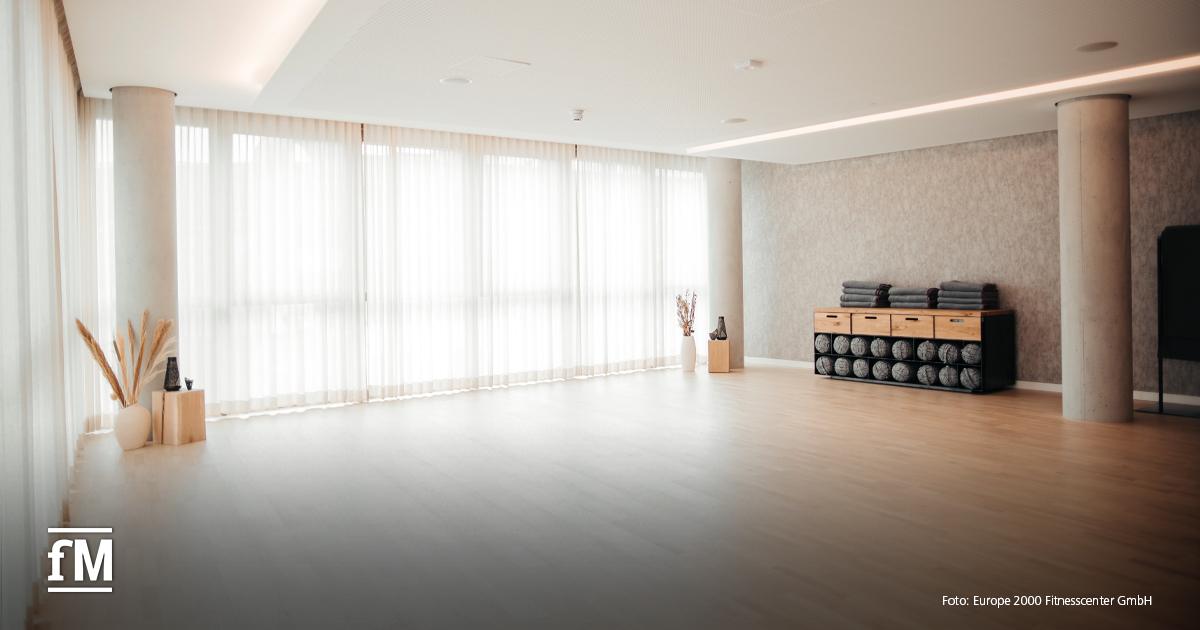 Heller, minimalistischer Kursraum mit Holzboden, Tageslicht und Equipment an der Wand