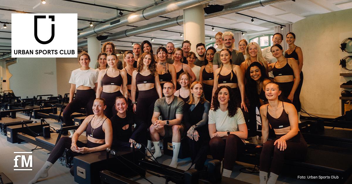 Erfolgsgeschichte Urban Sports Partner YTTP Eine Gruppe von Menschen in einem Fitnessstudio mit Reformern-Geräten. Oben links das Urban Sports Club Logo